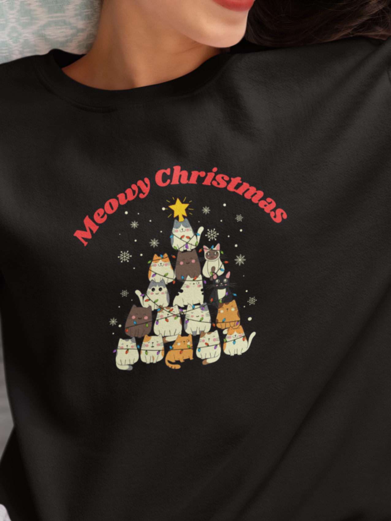 Person wearing a black sweatshirt with a Christmas-themed design and text.
