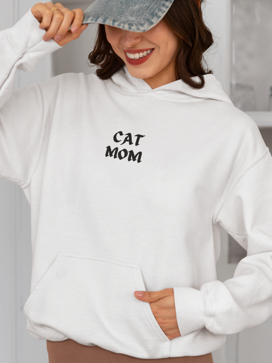 Person wearing a white hoodie with 'CAT MOM' text in a kitchen setting