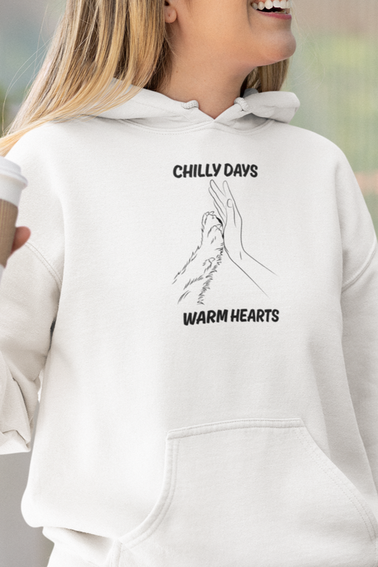 Woman wearing a white hoodie with text, holding a coffee cup outdoors.