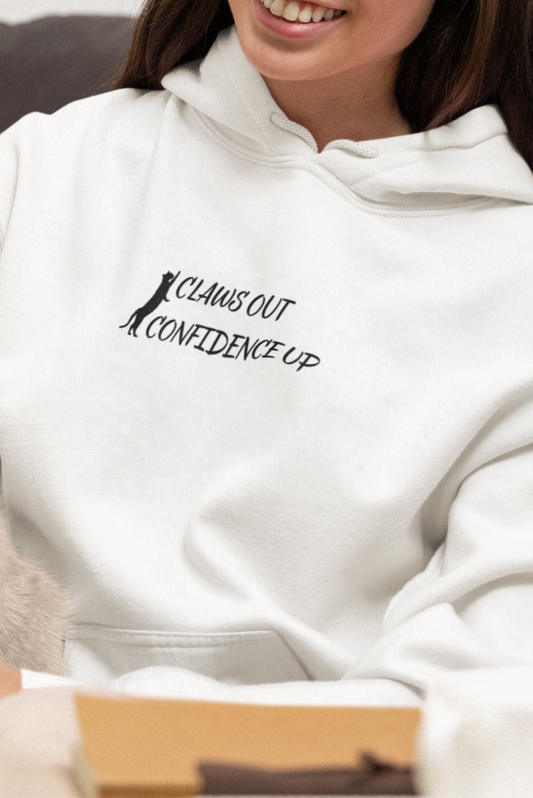 Woman wearing a hoodie with text, sitting on a couch with a cat.