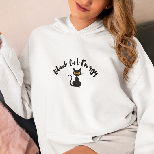 Person wearing a white hoodie with 'Black Cat Energy' text and cat graphic.