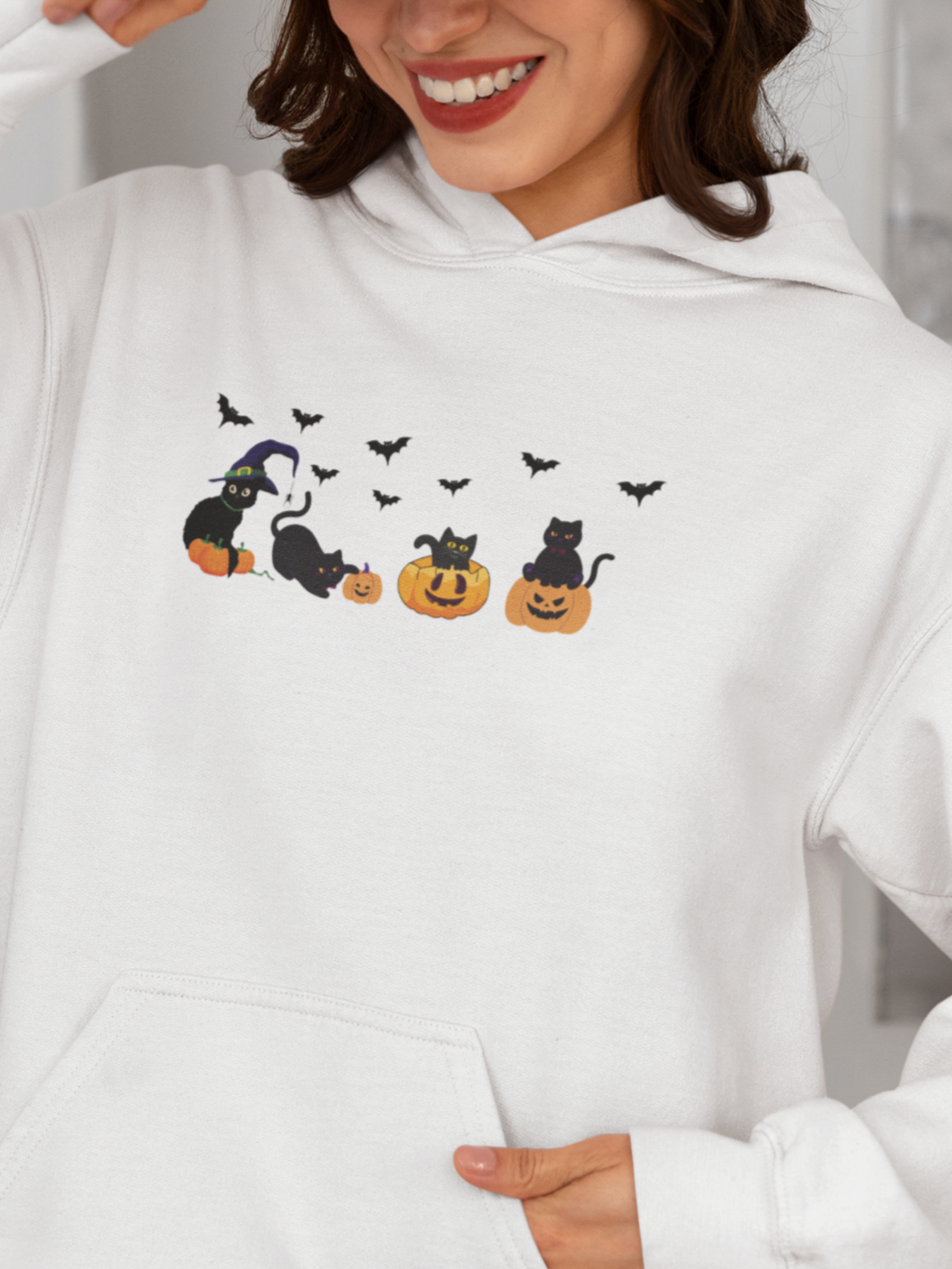 Person wearing a white hoodie with Halloween-themed design in a kitchen.