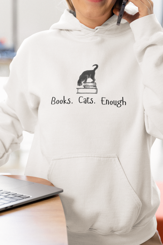 Woman wearing a white hoodie with a graphic and text, sitting at a desk with a laptop.