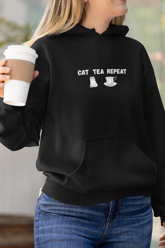 Woman wearing a black hoodie with text, holding a coffee cup outdoors.