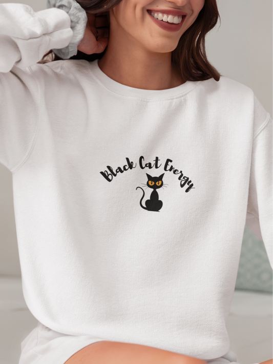 Person wearing a white sweatshirt with 'Black Cat Energy' text and black cat graphic.
