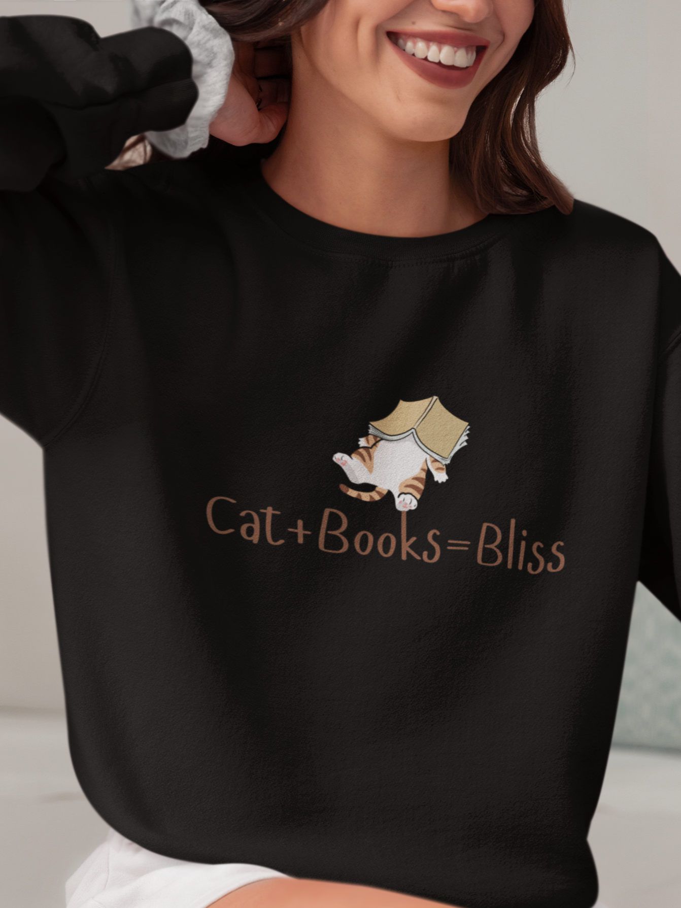 Person wearing a black sweatshirt with 'Cat + Books = Bliss' text and a cat graphic.