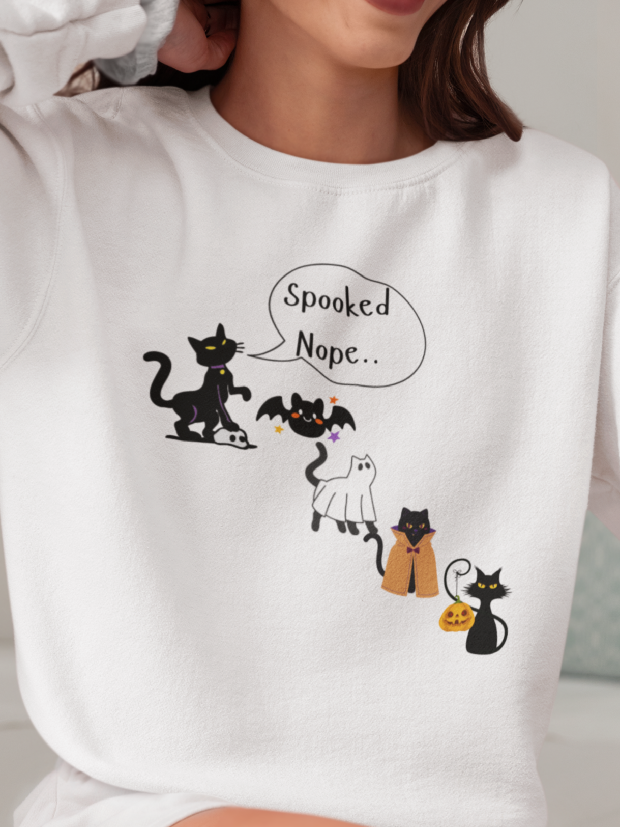 Person wearing a white sweatshirt with cartoon cat design and text.