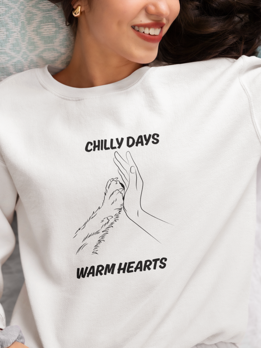 Person wearing a white sweatshirt with 'Chilly Days Warm Hearts' text and graphic.