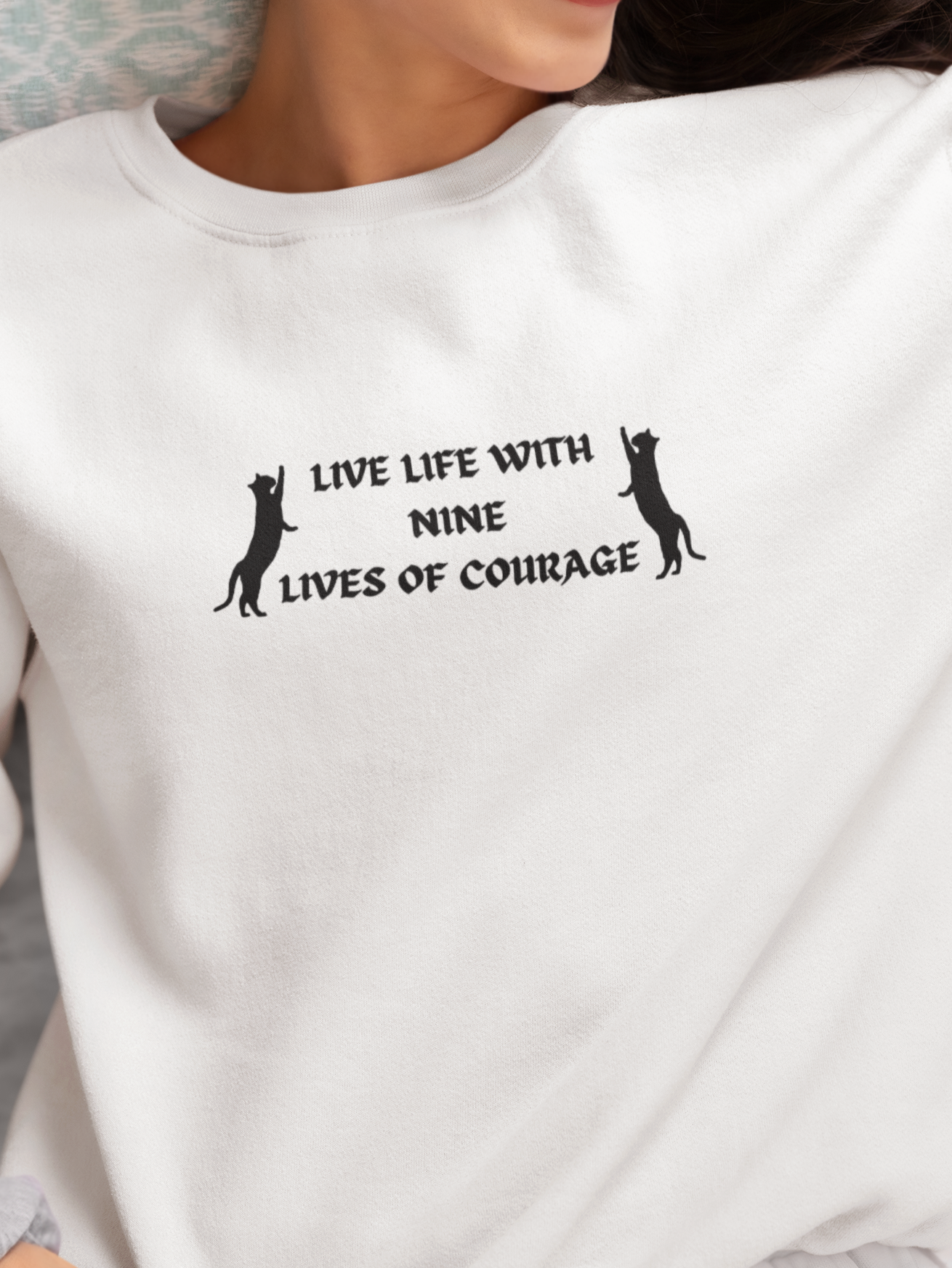 Person wearing a white sweatshirt with a black text design and two small black illustrations.