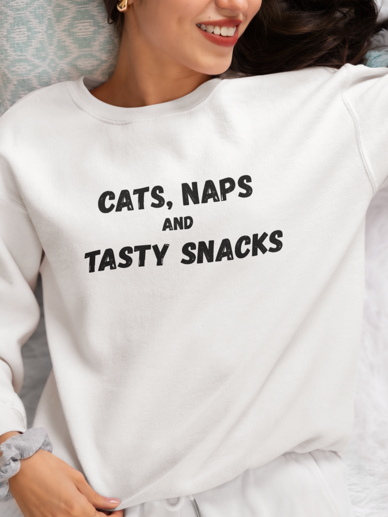 Person wearing a white sweatshirt with 'CATS, NAPS AND TASTY SNACKS' text.