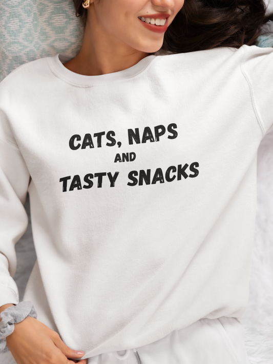 Person wearing a white sweatshirt with 'CATS, NAPS AND TASTY SNACKS' text.