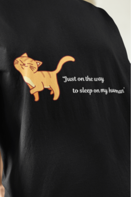 Person wearing a black t-shirt with a cat graphic and text.