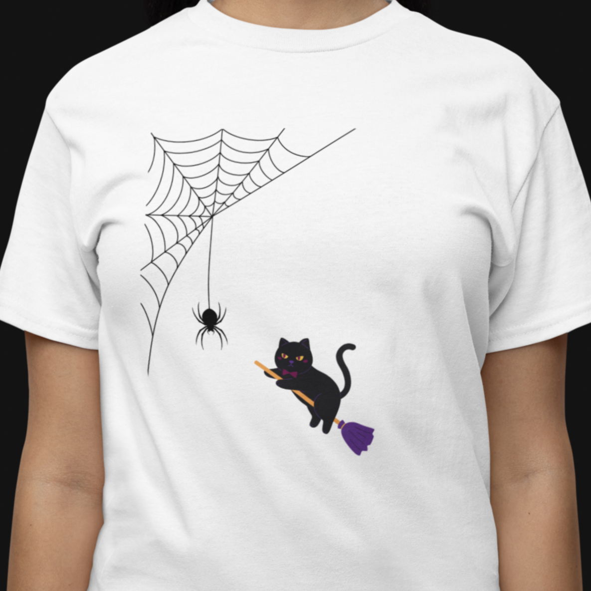 White t-shirt with a black cat, spider, and web design on a person against a black background