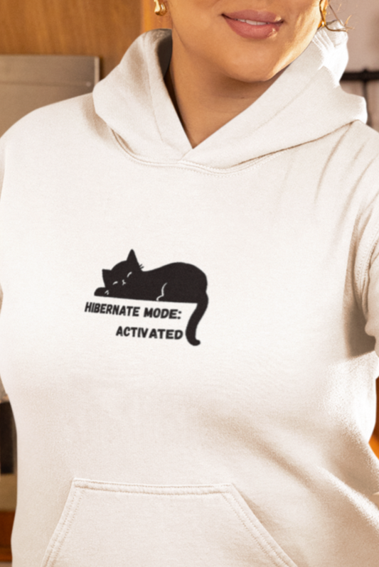 Person in a kitchen wearing a white hoodie with a logo, using a coffee maker.