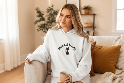 Person sitting on sofa in Black Cat Energy hoodie