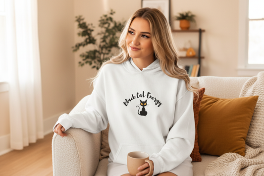 Person sitting on sofa in Black Cat Energy hoodie