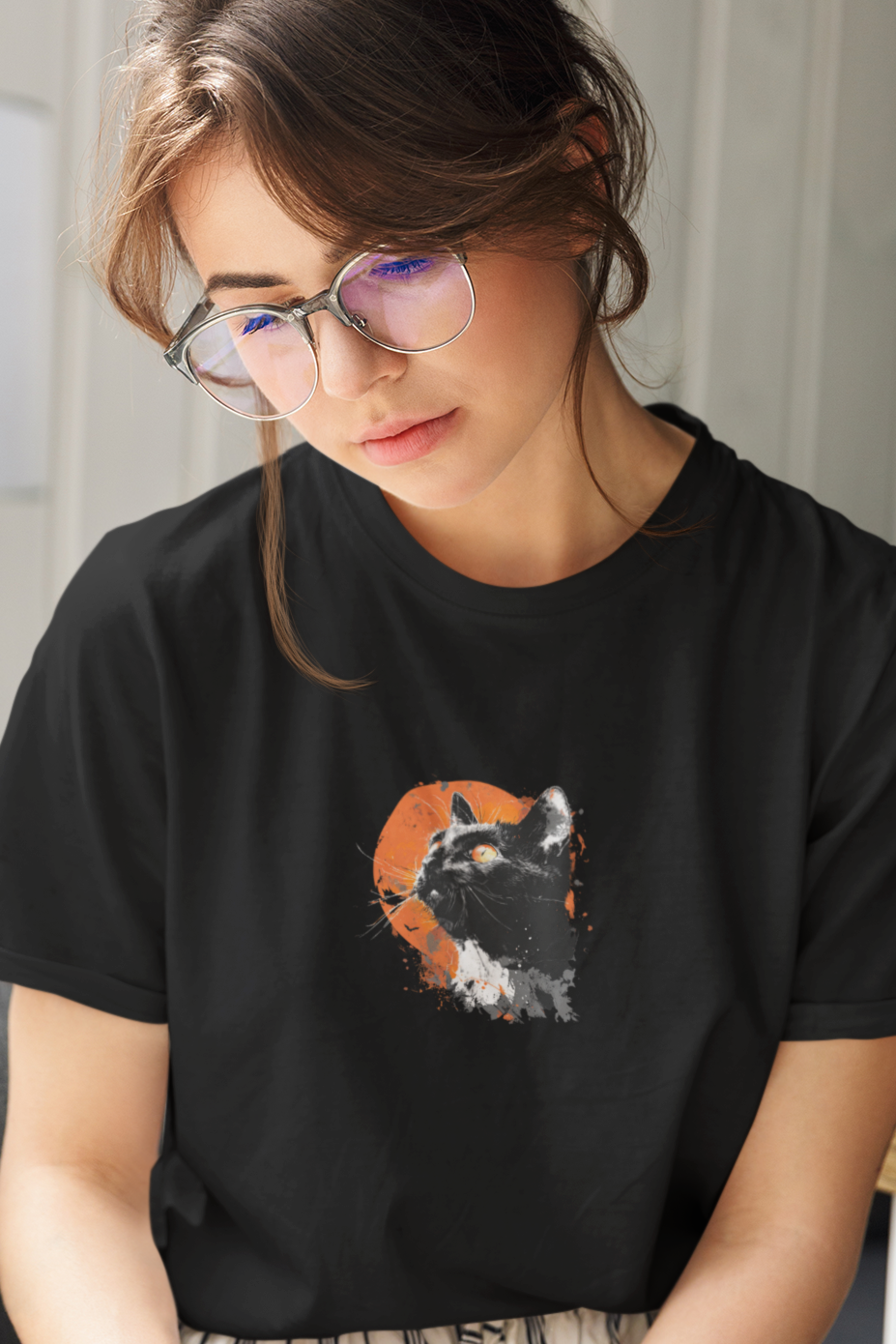 Woman reading a book wearing a black t-shirt with a graphic design.
