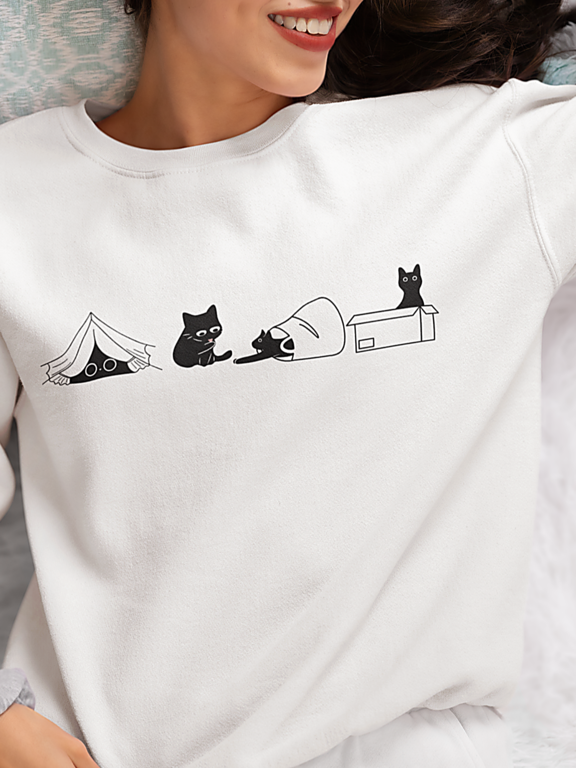 Person wearing a white sweatshirt with black cat illustrations.