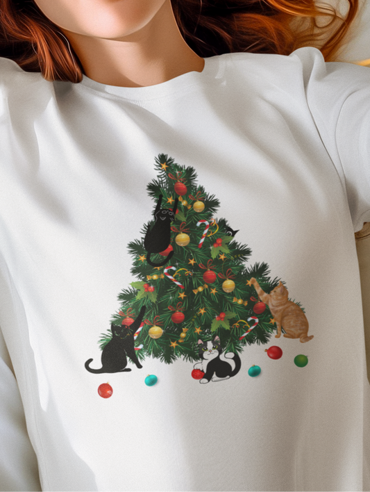Person wearing a white t-shirt with a Christmas tree and cat design, lying on a bed.
